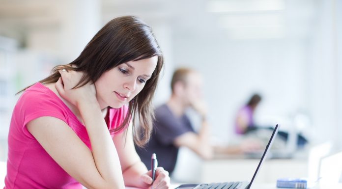 in the library - pretty female student with laptop and books working in a high school library (color toned image)